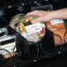 A hand putting food into a cold and ambient vending machine.