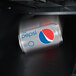 A close-up of a soda can falling into a white VEND MACH CD 10 SLT.