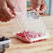 A person holding a D&W Fine Pack plastic container of raspberries.