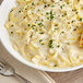 A bowl of noodles with Stouffer's Alfredo Parmigiana Sauce and a fork.