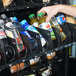 A hand reaching for a bottle of soda in a vending machine.