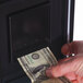 A person's hand inserting a dollar bill into a vending machine.