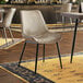 A Lancaster Table & Seating Mid-Century Black Chair with a Smokey Beige Vinyl Tufted Seat on a restaurant dining area table.