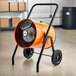 An orange and black Boltic portable electric salamander heater on wheels.