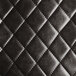 A close up of a black quilted vinyl surface on a Lancaster Table & Seating barstool cushion.