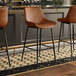 A row of Lancaster Table & Seating black barstools with cognac tufted vinyl seats.