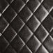 A close up of a black tufted leather chair cushion.