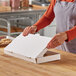 A person opening a Choice white corrugated flatbread box on a counter.