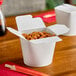 Two Emperor's Select white microwavable paper take-out containers filled with food.