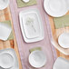 A table with white round plastic coupe bowls and plates on it.