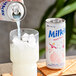 A hand pouring Milkis Peach Milk Soda from a can into a glass of ice.