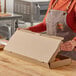 A person wearing a brown apron opening a Choice cardboard box.