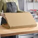 A woman in an apron holding a Choice kraft flatbread box.