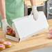 A man in a green shirt putting donuts in a white bakery box.