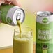 A hand pouring Evergreen Ready-to-Drink Matcha Bubble Tea from a green can into a glass.