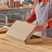 A person holding a Choice kraft corrugated bakery box filled with cookies.