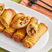 A white plate with several fried Chef One Buffalo Chicken Egg Rolls.