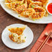 A plate of Chef One chicken and vegetable dumplings with dipping sauce and chopsticks.