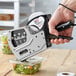 A hand using a DayMark Speedy Mark 5 metal labeler to label a container of salad