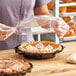 A person holding a Good Natured clear plastic domed lid over a pie.