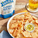 A bowl of Issa's Classic Sea Salt Pita Chips on a table with a glass of beer.