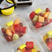 A group of plastic containers of fruit salad with DayMark yellow date coder labels.