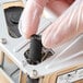 A person wearing gloves removes the black ink roller from a small DayMark Speedy Mark 3 device.