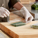 A person in gloves holding a clear plastic Good Natured herb container with green onions.