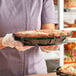 A person holding a pie in a clear plastic pie base.