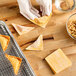 A gloved hand holds a triangle-shaped wonton wrapper.