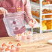 A woman holding a Good Natured clear plastic container with cupcakes.