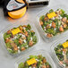 A group of DayMark fluorescent orange date coder labels on plastic containers of salad.
