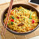 A bowl of Twin Marquis pre-cooked frozen yakisoba noodles with vegetables and chopsticks.