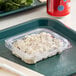 A clear Good Natured tamper-evident plastic container with food inside on a white tray.