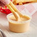 A person dipping a french fries into a cup of Terry Ho's Original Yum Yum Sauce.