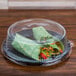 A clear dome lid on a table over food in a plastic container.