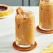 Two glasses of iced coffee with cookies on top on a table.