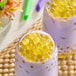 Two glasses of milk with purple and yellow bubbles, a close up of a glass of purple liquid with yellow balls.