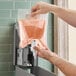 A hand using Lavex foaming antibacterial hand soap in a plastic bag.