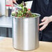 A woman stirring a salad in a Vollrath stainless steel bain marie pot.