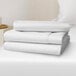 A close-up of a stack of white Oxford Micro Superblend king size fitted sheets.