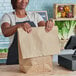 A woman holding a Duro brown paper barrel sack at a register in a grocery store.