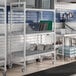 A Cambro Camshelving Premium Drying Rack Cart in a kitchen with metal shelves.