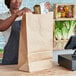 A woman holding a Duro brown paper barrel sack at a grocery store counter.