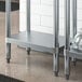 A Regency galvanized steel adjustable undershelf for a work table with metal legs.