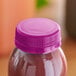 A purple plastic juice bottle with a violet tamper-evident cap on a table.