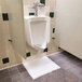 A Quick Dam absorbent drip mat under a urinal with a blue spot.