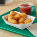 A white paper food tray with tater tots and ketchup.