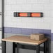 A Boltic black electric infrared heater on a wood table in a room.