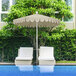 A white patio table with two chairs under a 7.5ft patio umbrella with a scalloped edge.